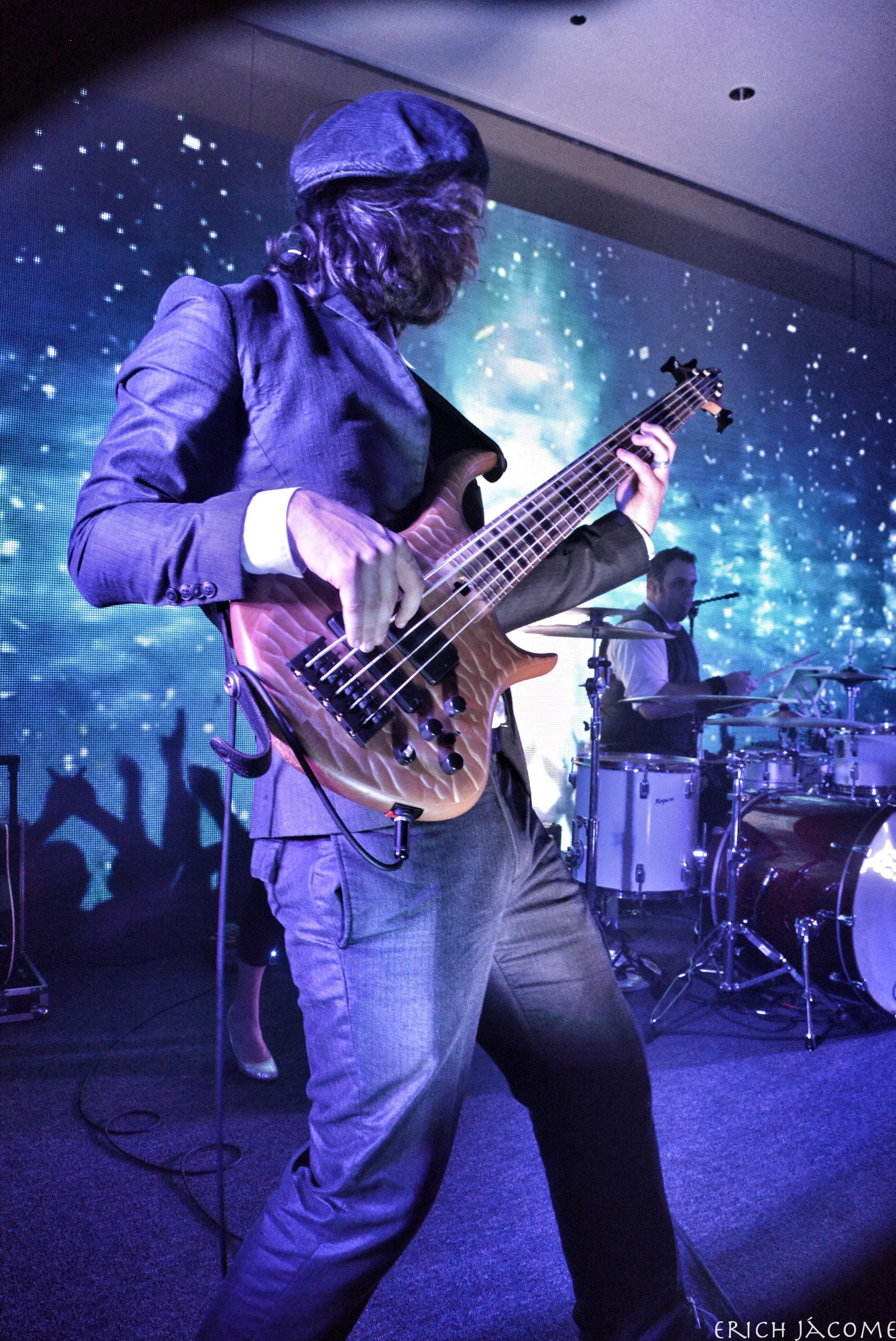The band's bass player in a flat cap under blue light