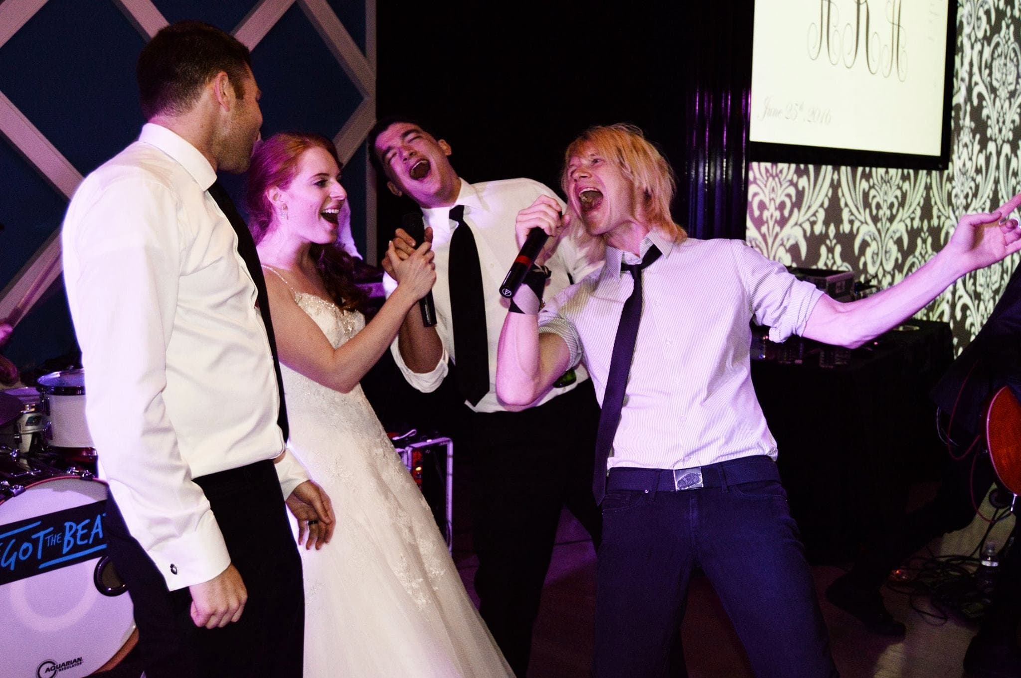 A bride and groom singing on stage with the band's two singers