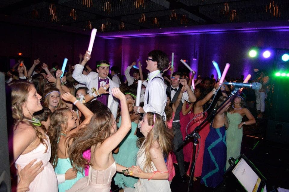 Guests dancing with glow sticks under purple and blue light
