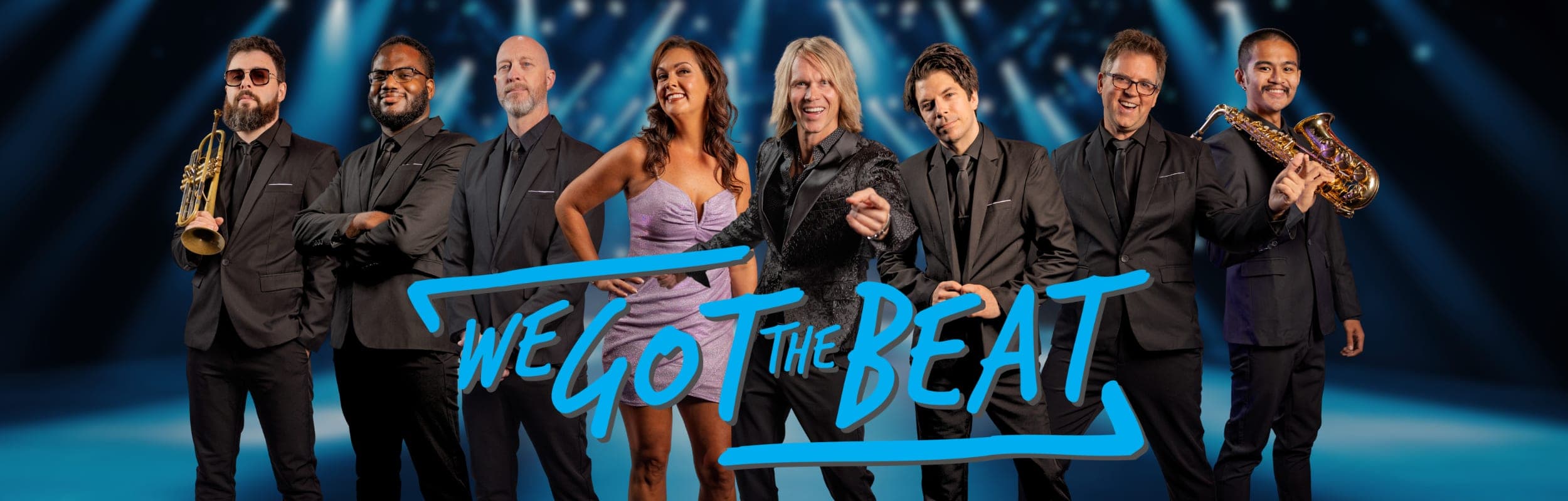 We Got The Beat, the eight-piece party band, in black on a blue-lit stage with the band's logo across the front