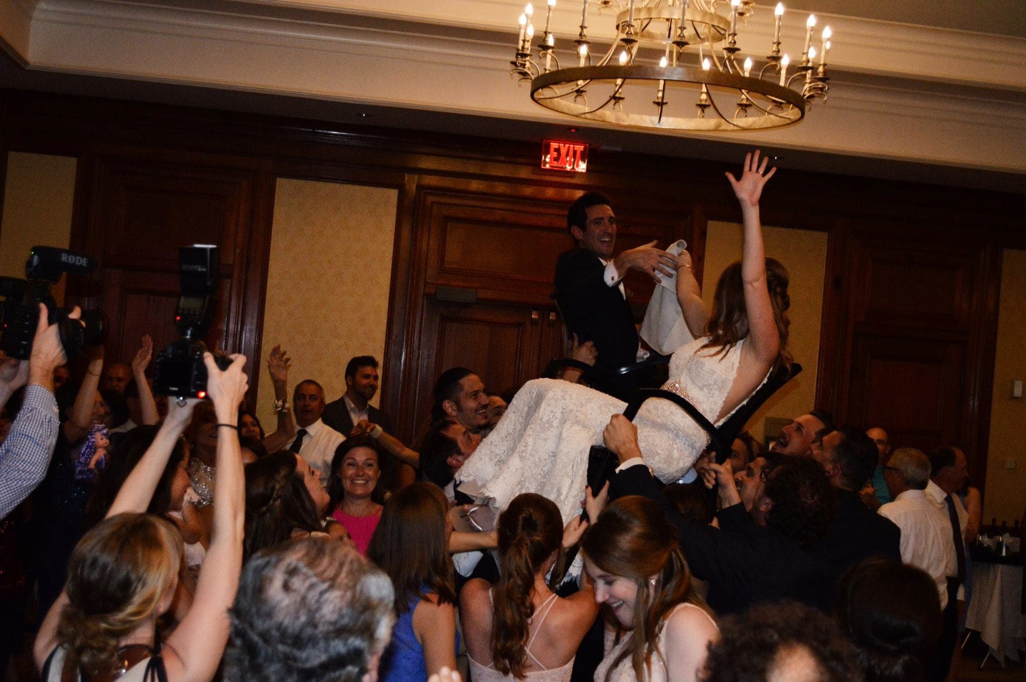 Wedding guests on a packed dance floor with their arms in the air